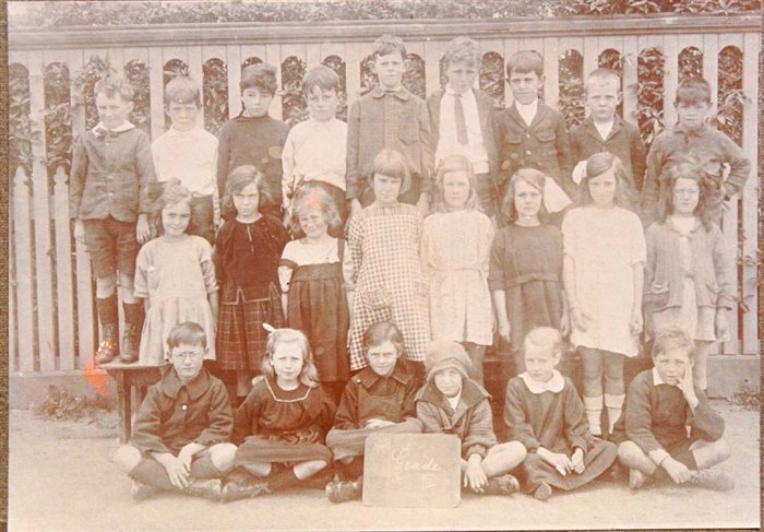 Image of Students from the first Penders Grove School standing against the fence outside. The fence is part of the Tower House property. [LHRN1096]