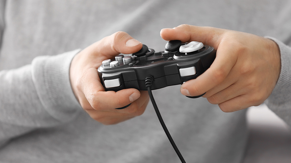 Close up of hands holding a gaming handset console and the person is wearing a grey sweatshirt