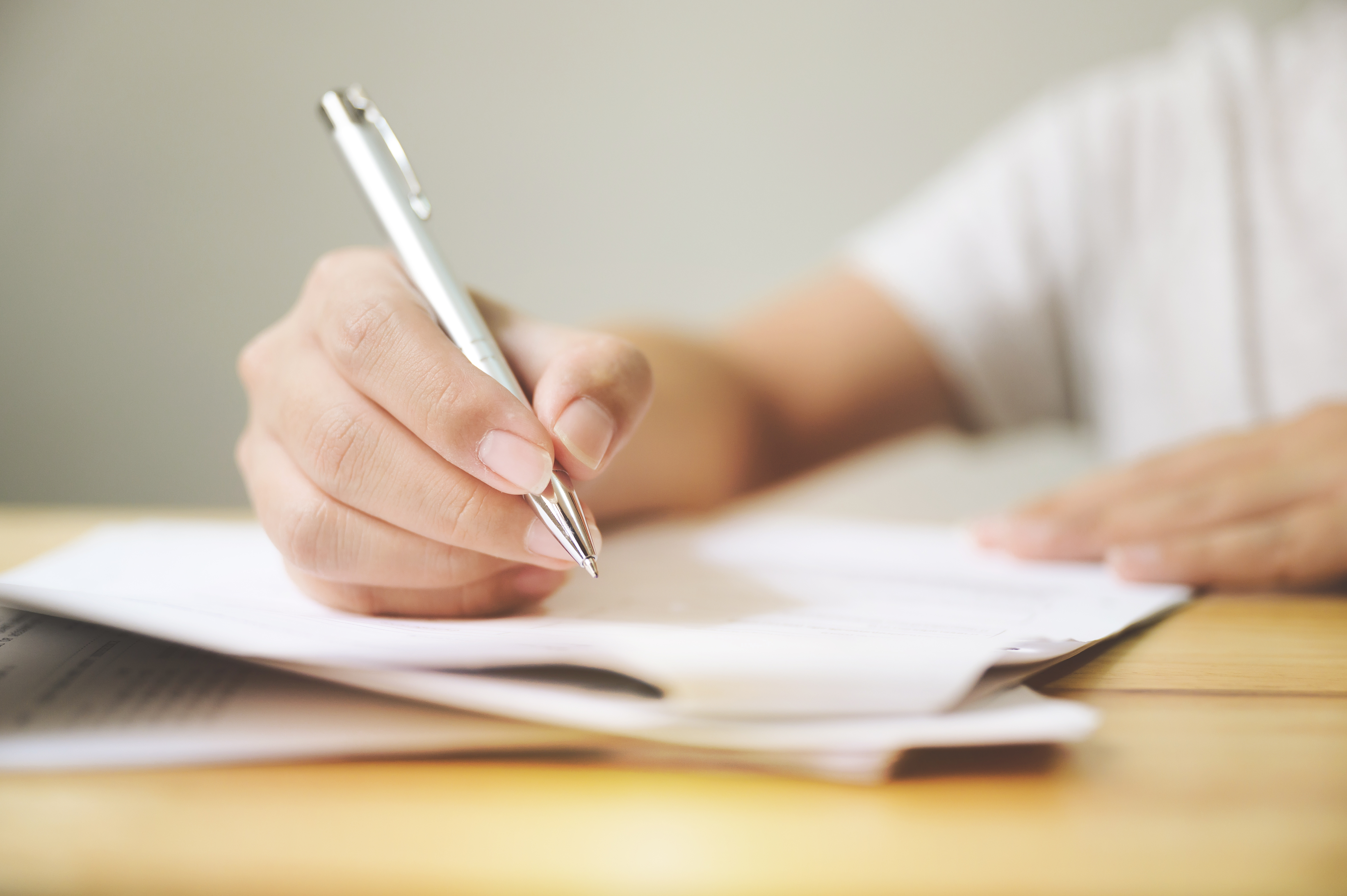 image: A close up of someone signing a document in pen