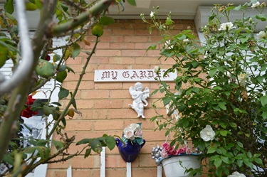 Margaret's garden. Brick wall decorated with hanging cupid statue and 