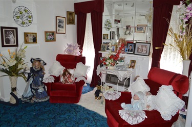 Margaret Simmons' Lounge room features red furniture and porcelain dolls