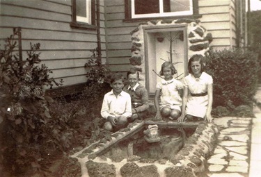 Homemade goldfish pond in the backyard of 4 Storey Rd, Reservoir 1939. Kenneth Latham far left, Valarie Latham 3rd from left [LHRN5437-21]