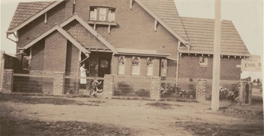 Breese family home with Lima Breese and child. The two storey brick bungalow is attached to a boot/shoe shop that was on Edwardes St.
