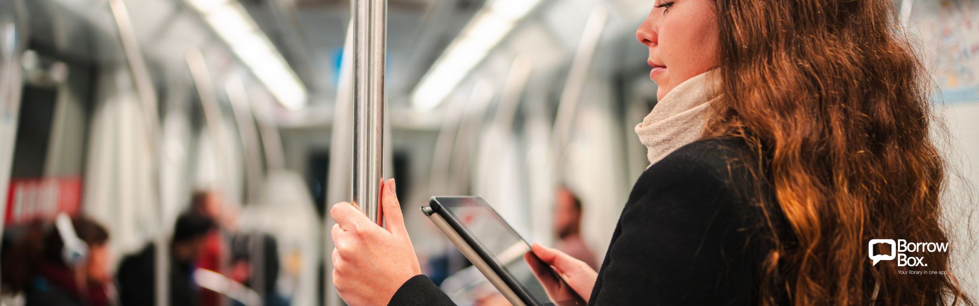 A woman looking at a small tablet while riding in public transportation.