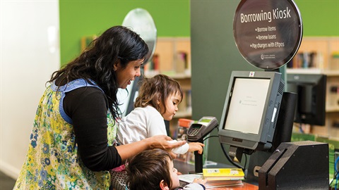 a woman and 2 kids in the borrowing kiosk